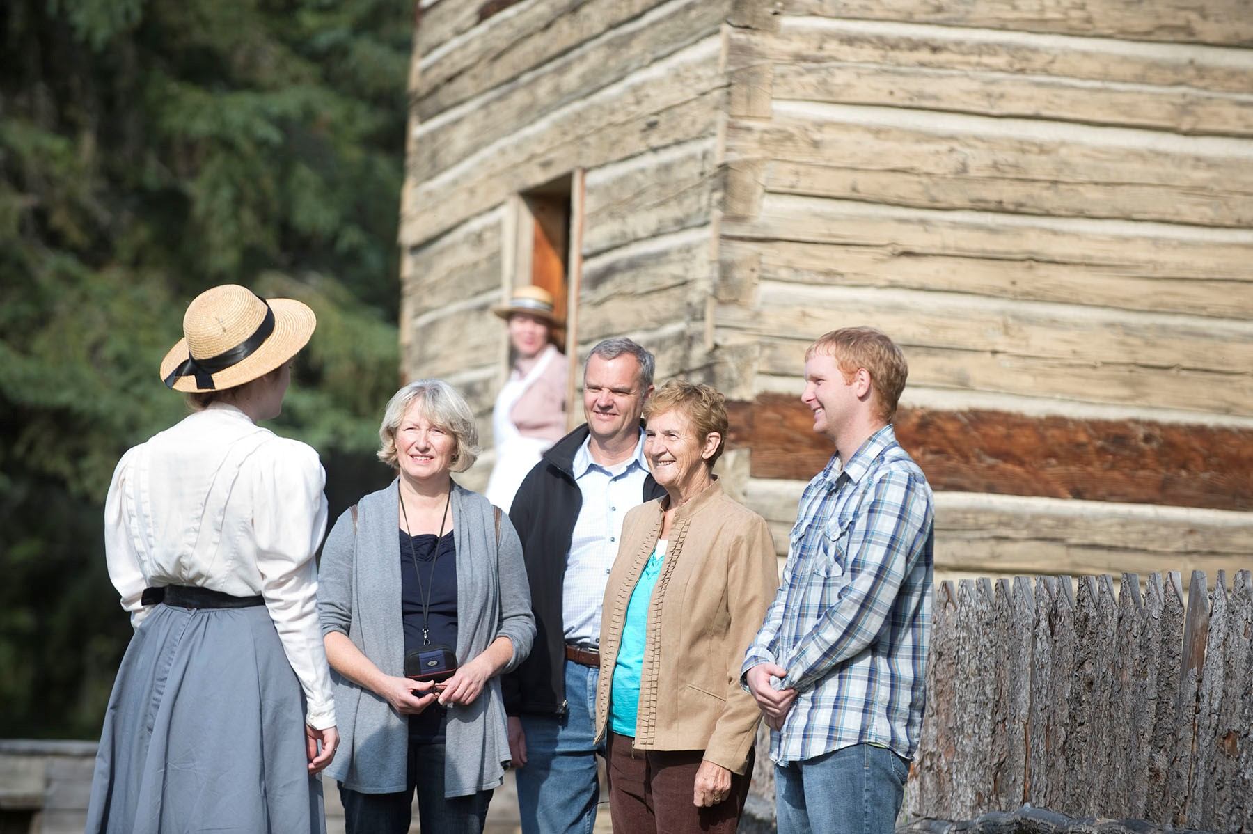 Interpreter speaking to visitors outside a log building at Historic Dunvegan.