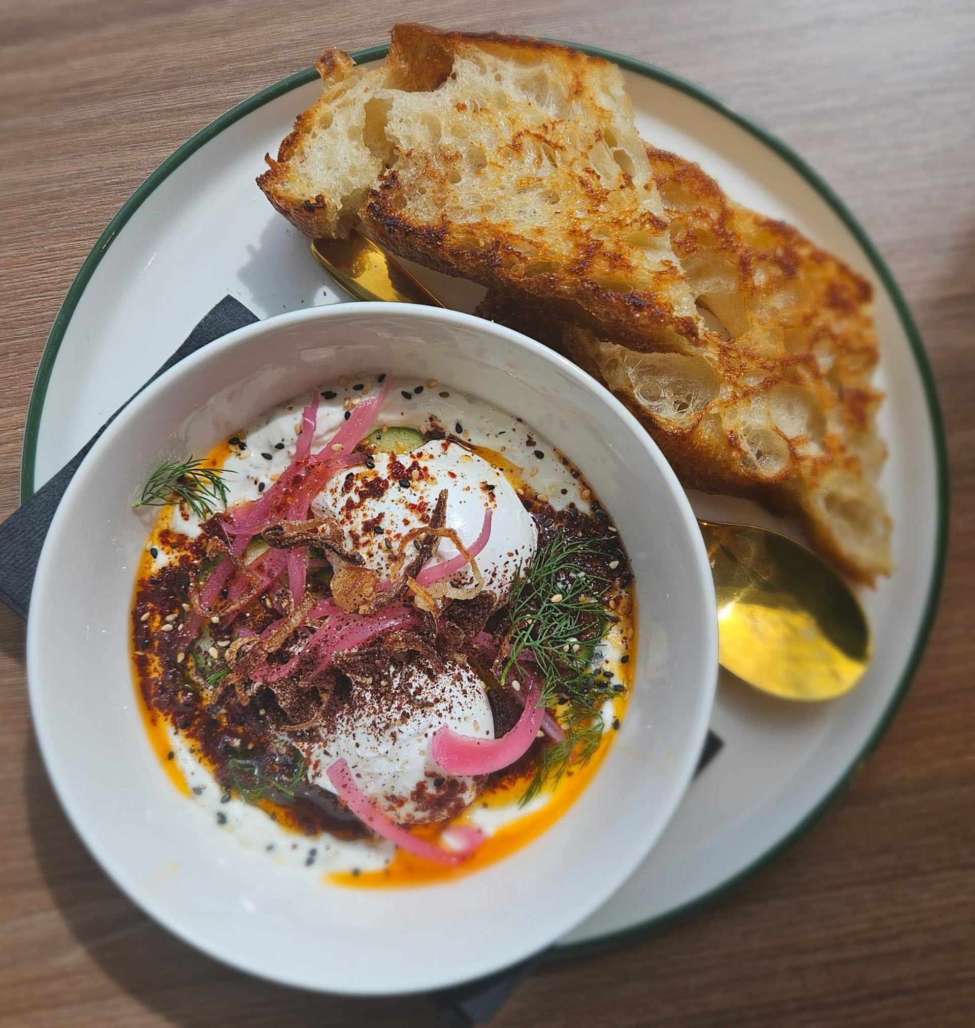 Bowl of creamy dish with herbs and onions, served with toasted bread and spoon.