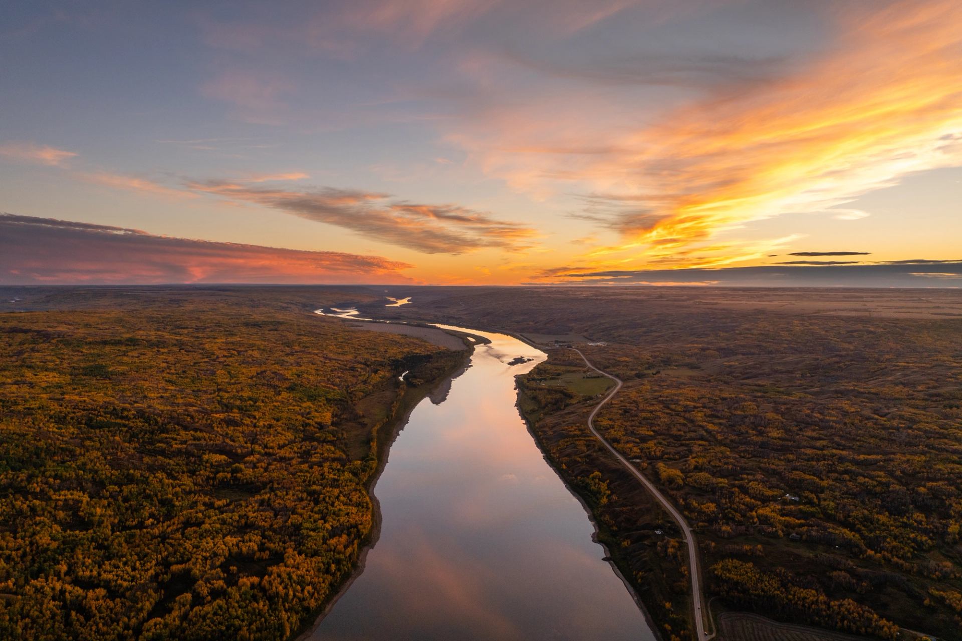 Peace River winding through autumn forest under sunset sky near Peace River Cabins.