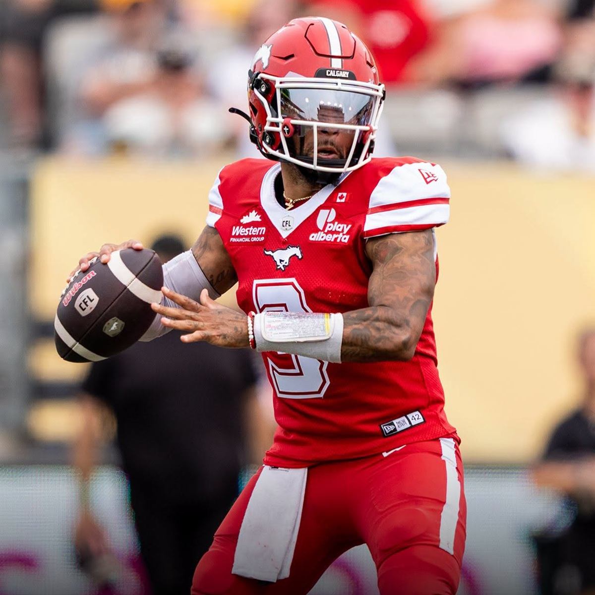 Calgary Stampeders quarterback in a red uniform grips a football during a game.