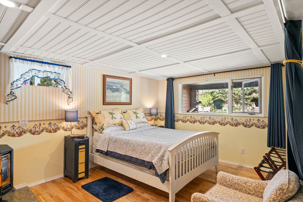 Bright bedroom with queen bed, cozy chair, and large window.