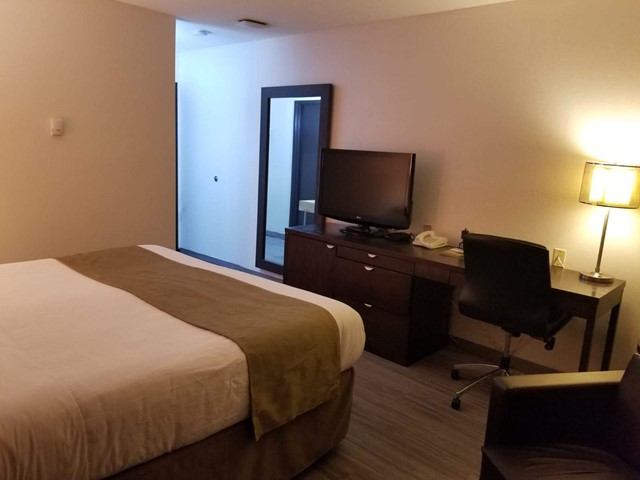 Travelodge by Wyndham guest room with bed, desk, chair, TV, and lamp.