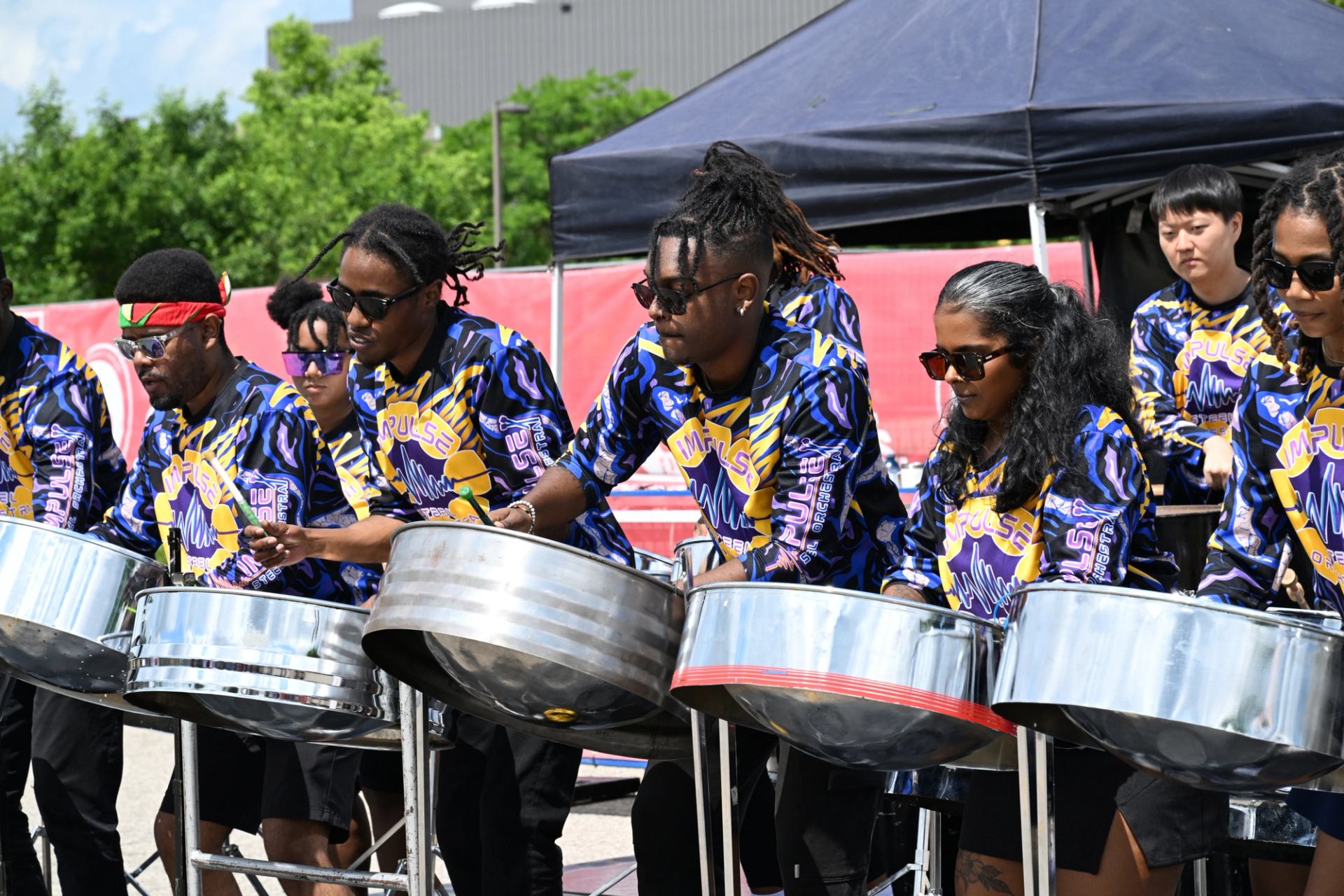 Steel drum players perform outdoors in colorful shirts at The Good Games.