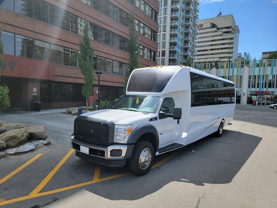 White shuttle bus parked on a city street by MC Limousine.