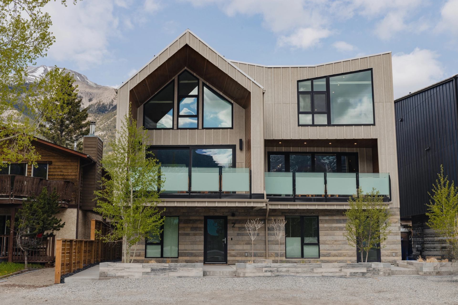 Modern mountain retreat with large windows, wood accents, and scenic backdrop.