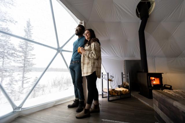 Couple looking out window of Camping Dome at elevated Escapes.