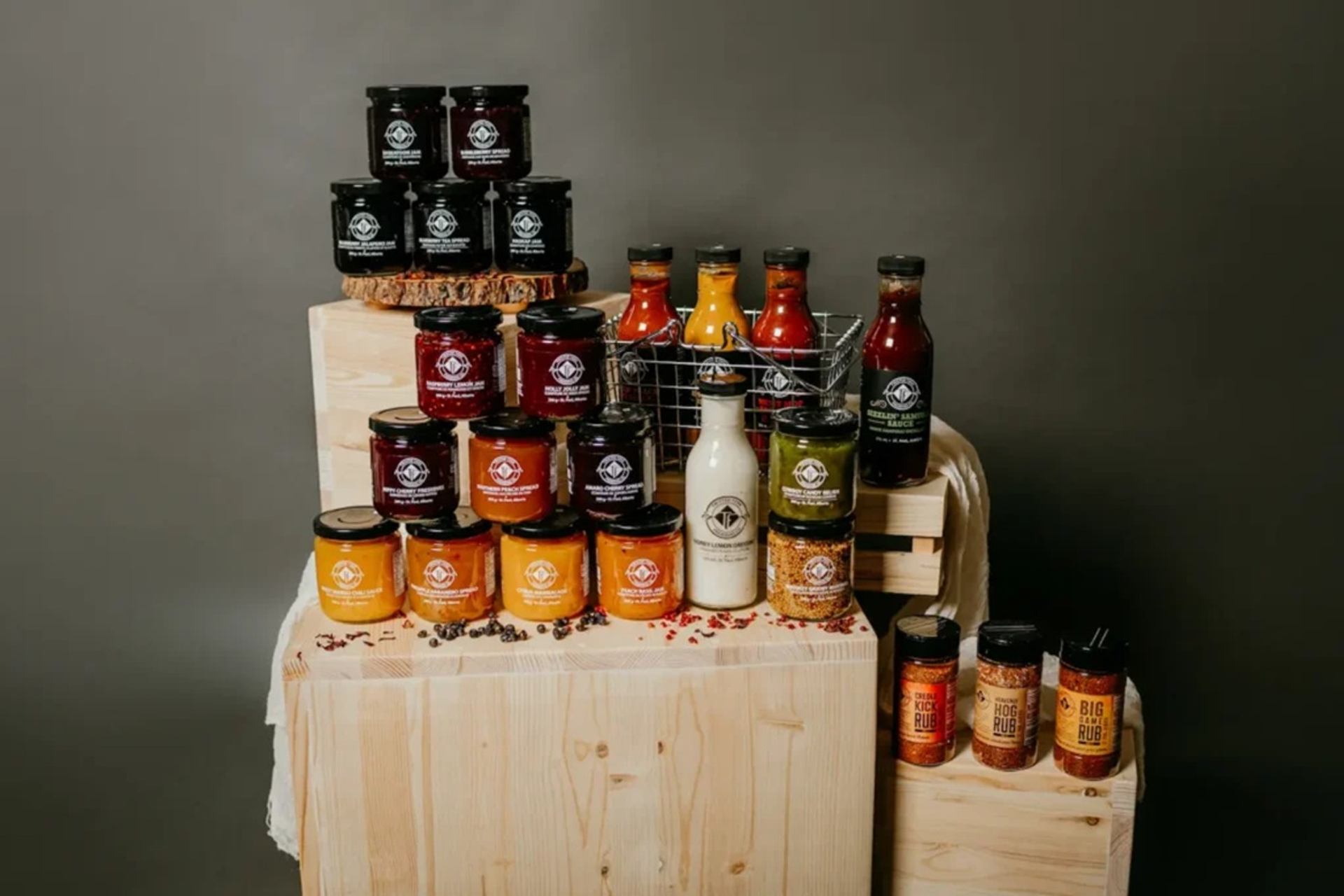 Assorted sauces, rubs and condiments in jars and bottles arranged on wooden crates.