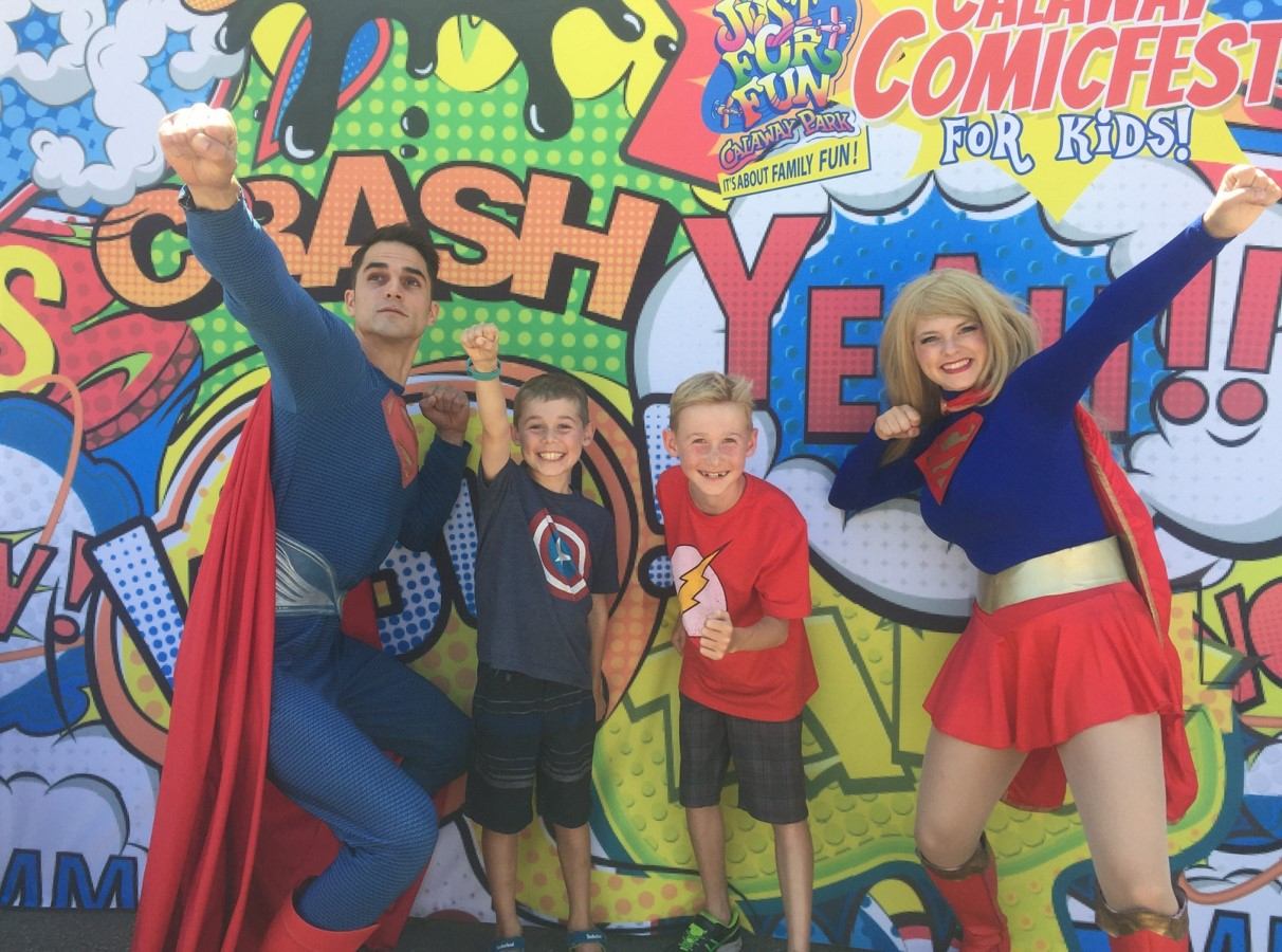 Kids and costumed heroes pose in front of colorful comic backdrop at Calaway Comic Fest for Kids.