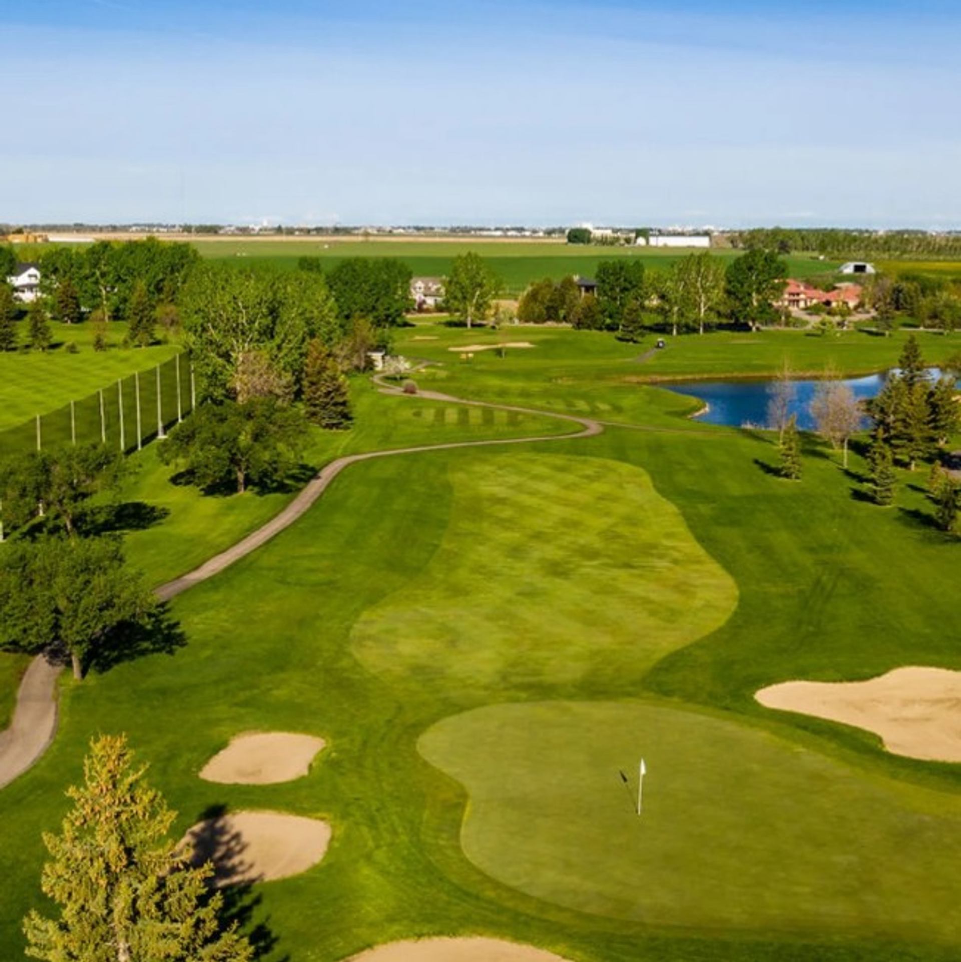 Aerial view of golf course featuring sand bunkers, fairways, and a pond