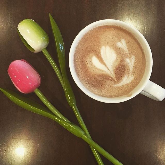 Cup of latte with heart art and two decorative tulips at Waters Edge Pub & Café.