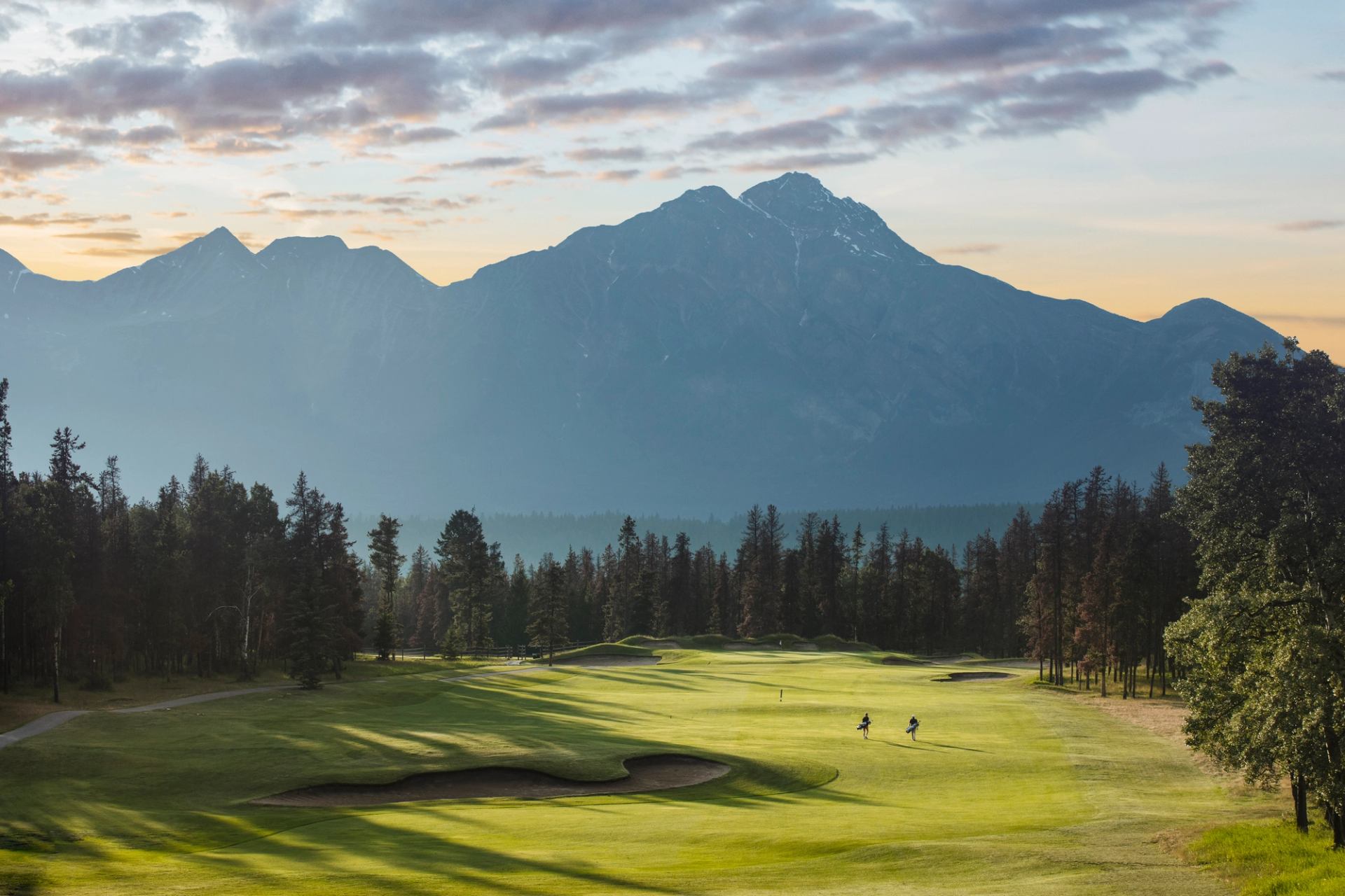 Picturesque view of a pair of golfers at sunset towards Pyramid Mountain.