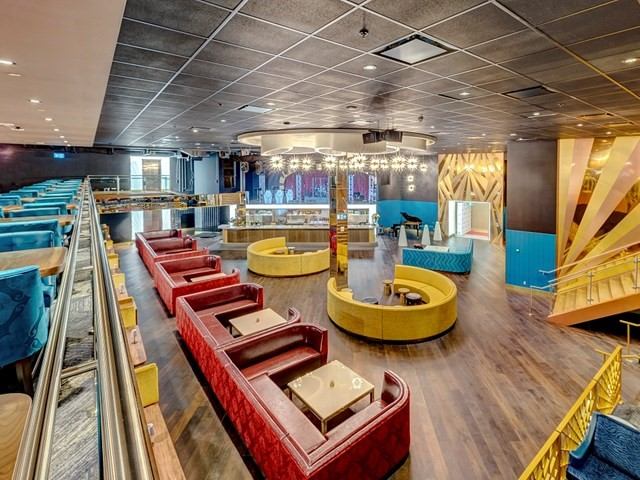 Casino lounge seating and gaming tables with carpeted booths and bright light fixtures inside.