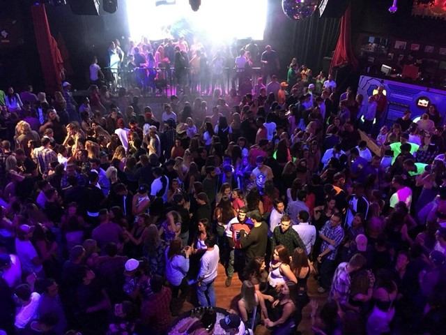 Crowded dance floor with colorful lights at Cowboys Dance Hall.