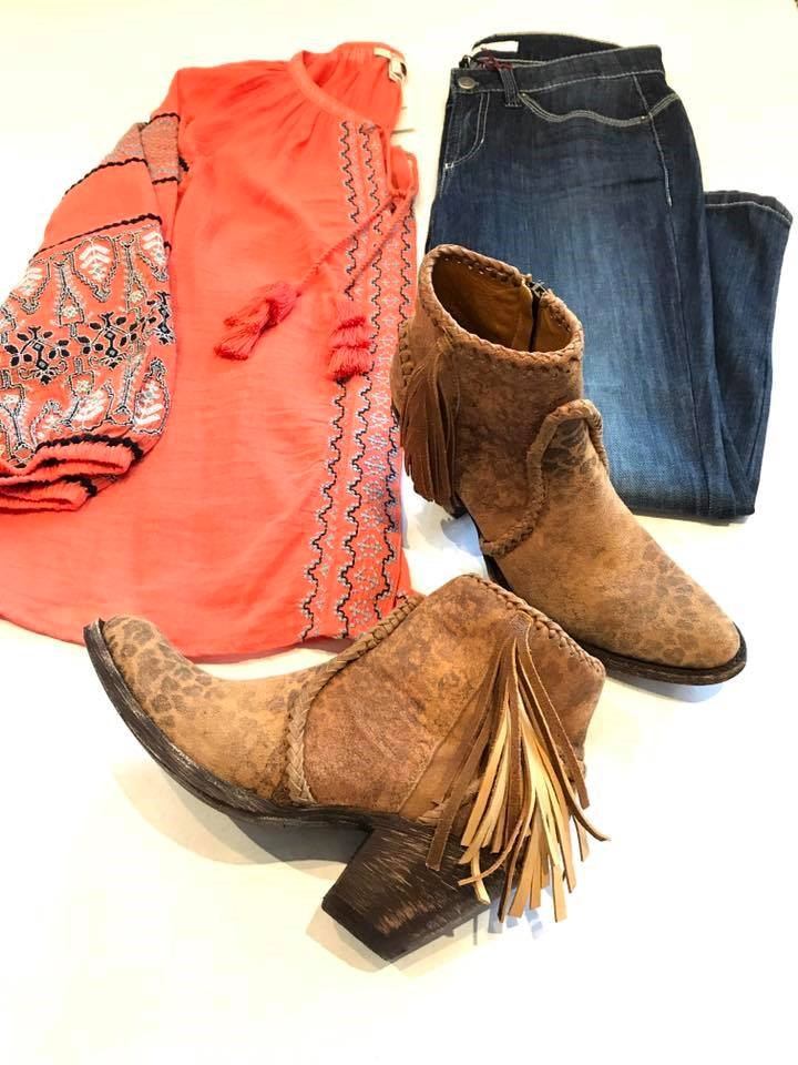 Cowboy boots, jeans, and a bright orange blouse displayed on a white background.