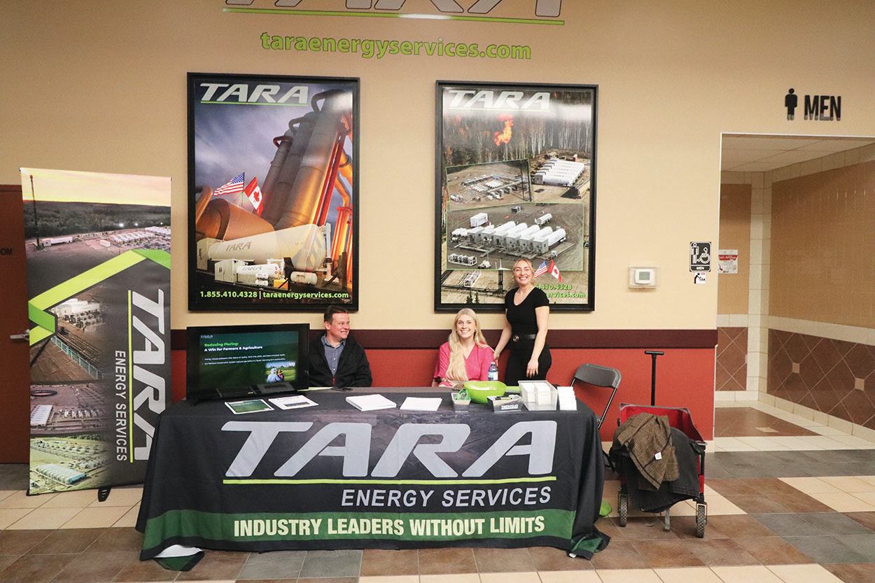 Energy services exhibitor booth with banners and staff speaking with visitors inside an event hall.