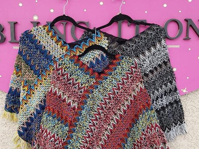 Colourful woven ponchos on hangers in front of pink Bali Bling sign.