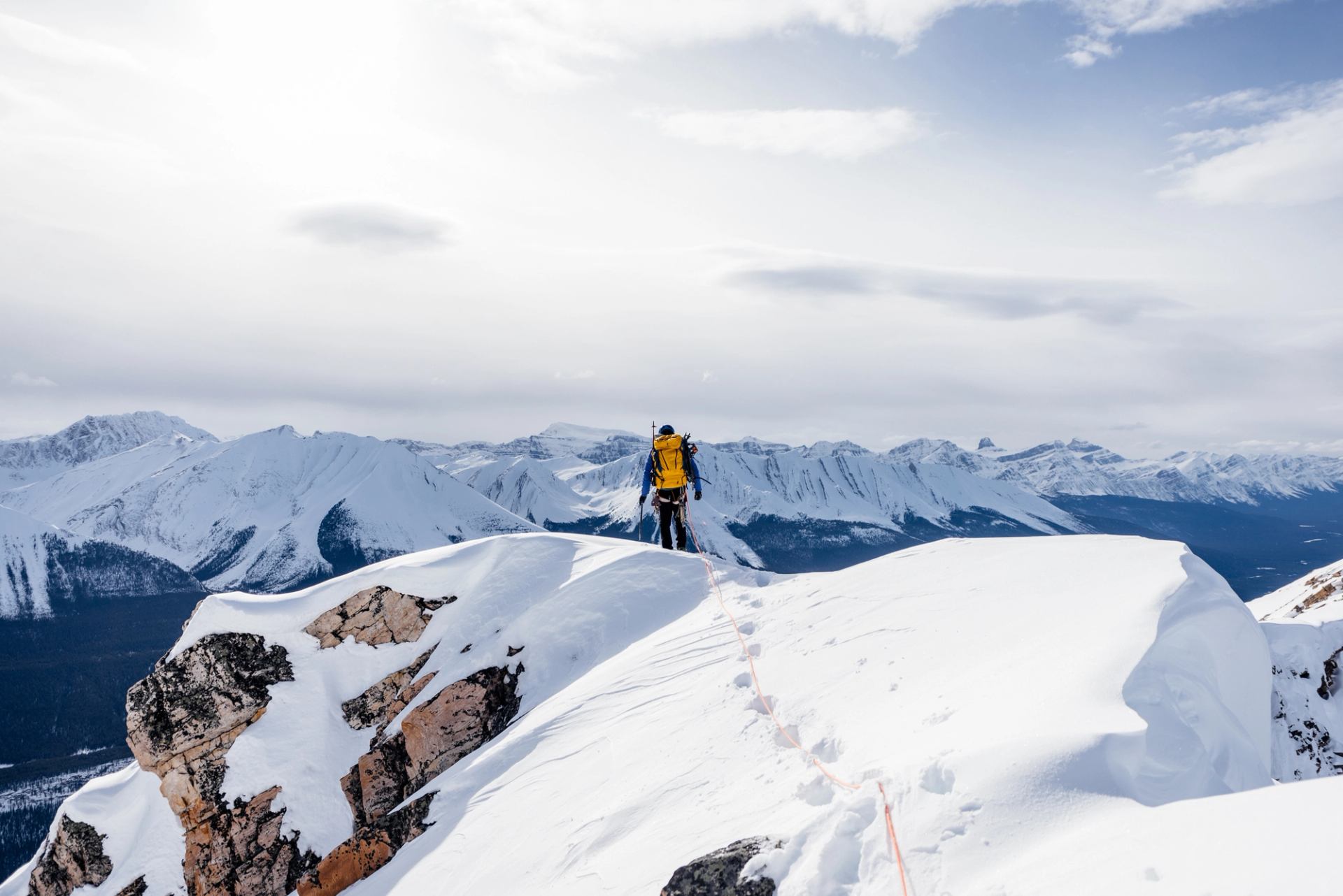 Solo climber stands at summit, overlooking mountains after ice climbing in Jasper National Park.
