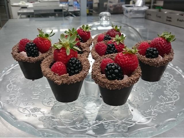 Chocolate cups filled with fresh raspberries and blackberries on a glass platter.