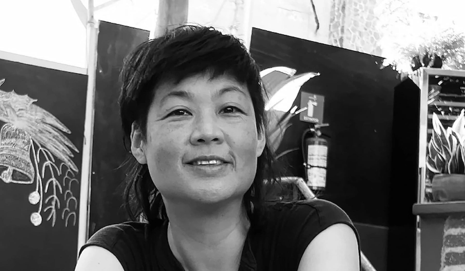 Person sitting indoors with chalkboard art, fire extinguisher and plants in background.