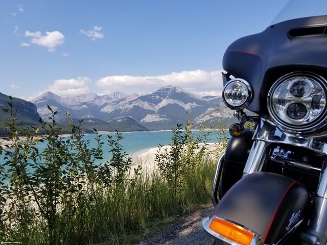 Harley-Davidson parked by lake with mountain views on scenic ride.