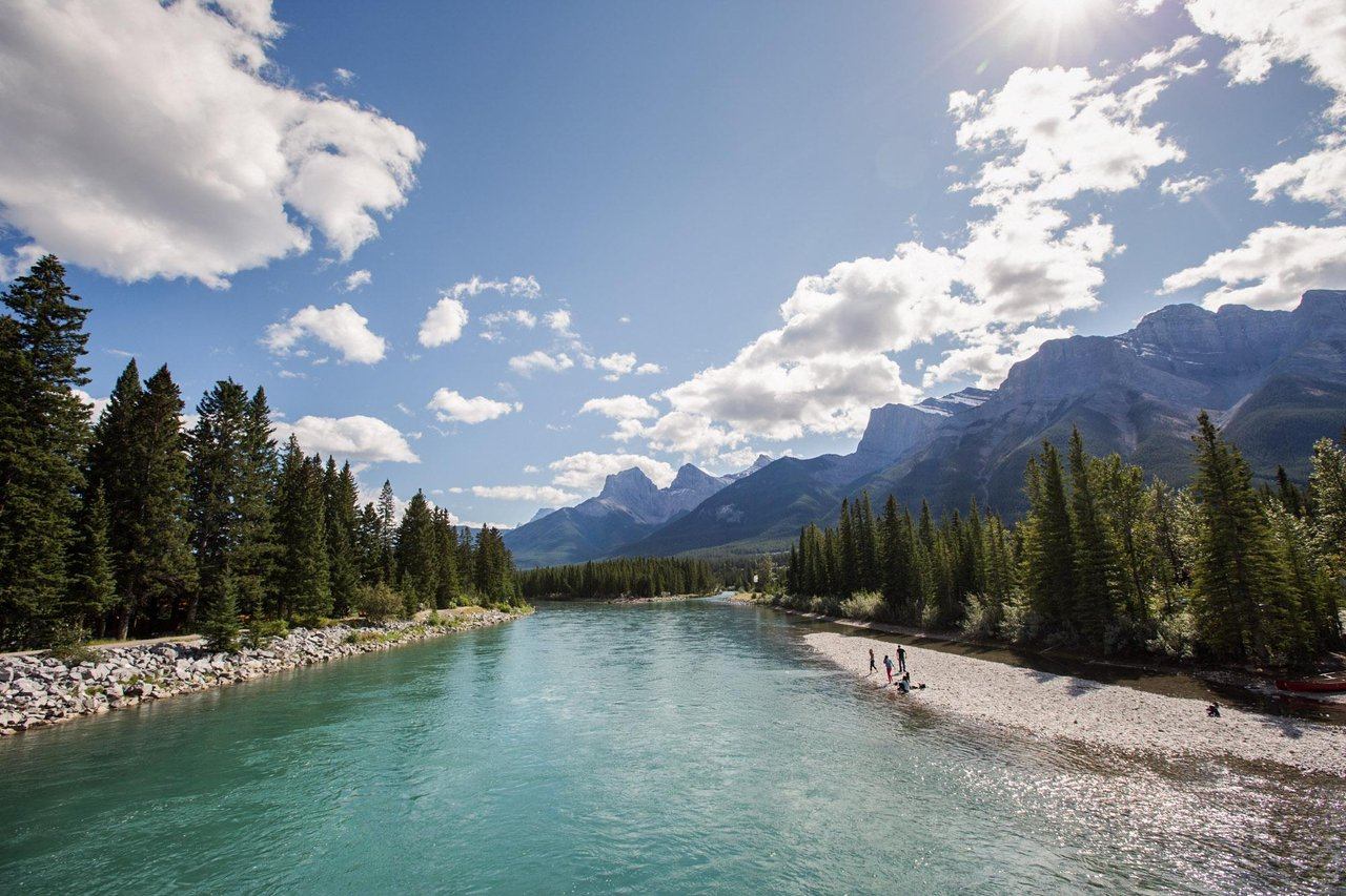 A family enjoying the Bow River with the Three Sisters mountains in the background