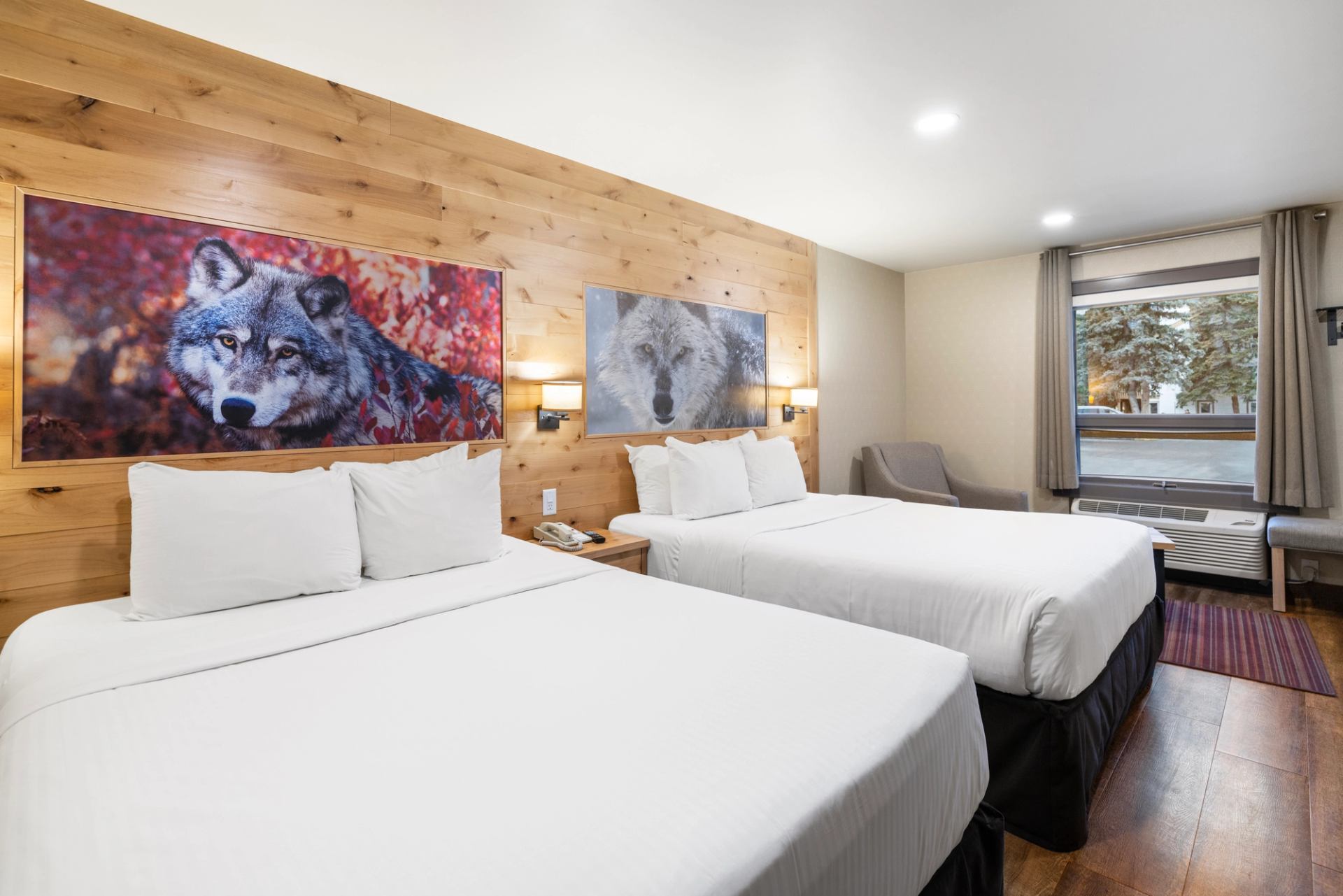 Two queen beds side by side with photos with a wood wall in behind and two photos of wolves.