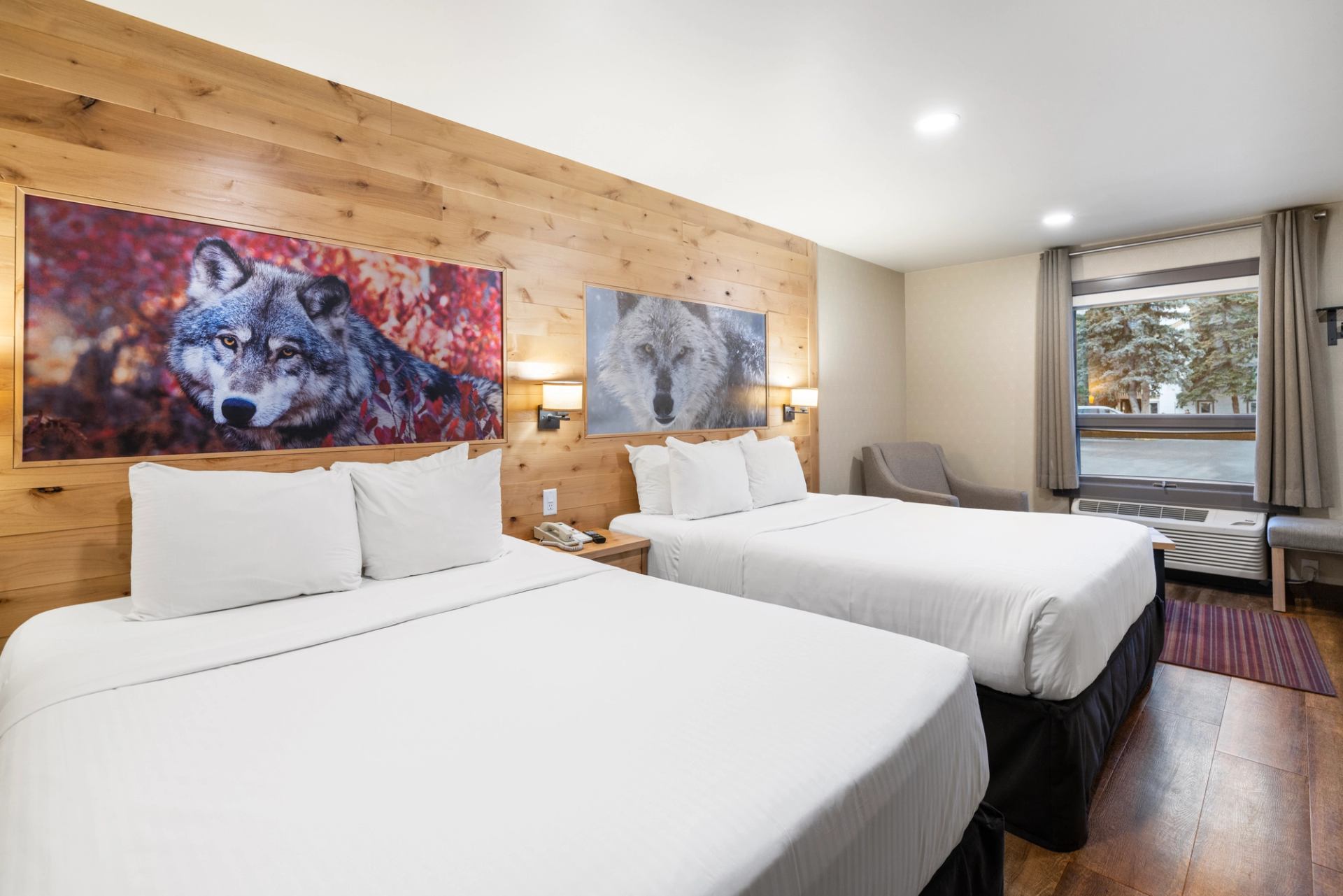 Two queen beds side by side with photos with a wood wall in behind and two photos of wolves.