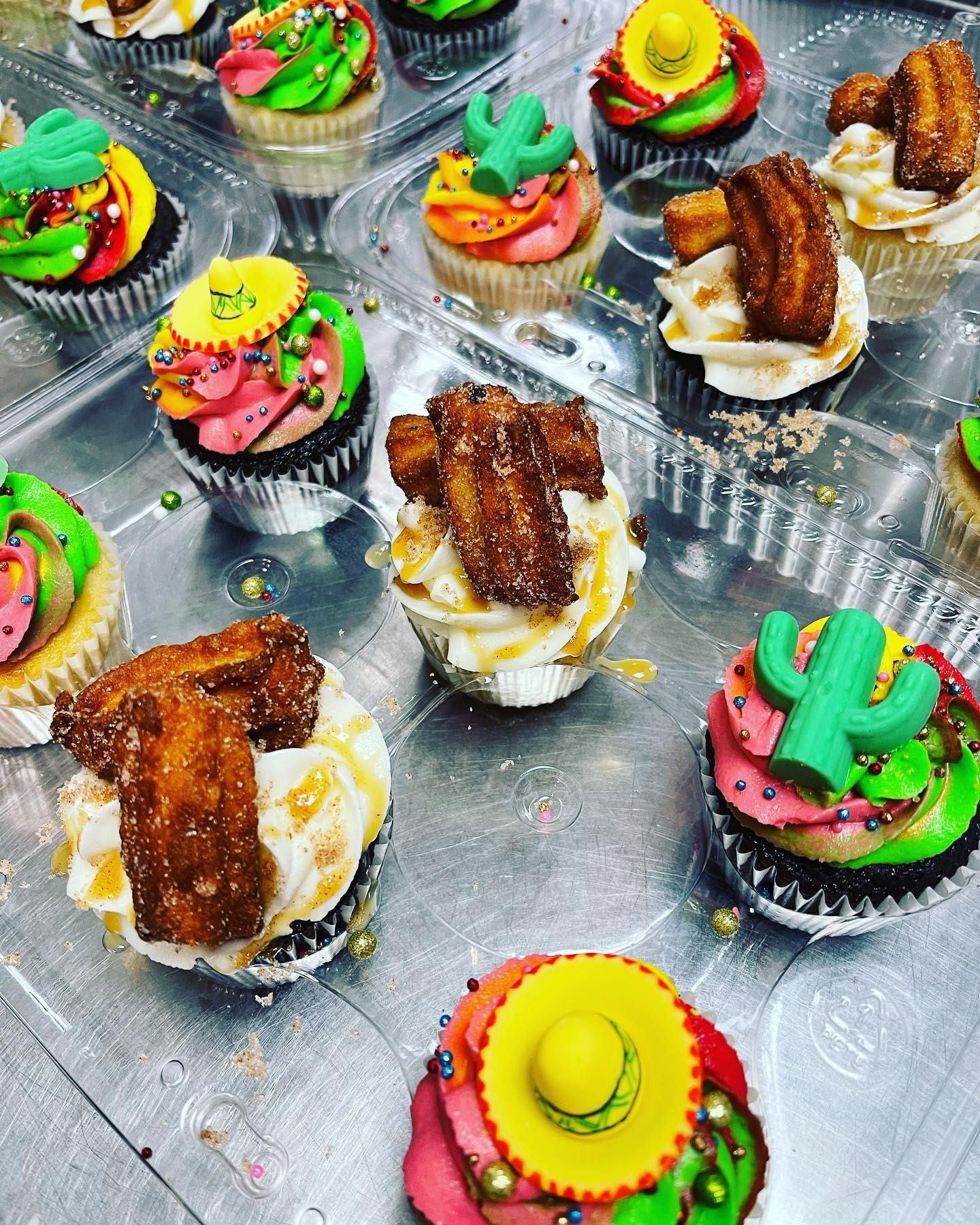 Colorful fiesta cupcakes decorated with churros, cactus toppers, and vibrant frosting.