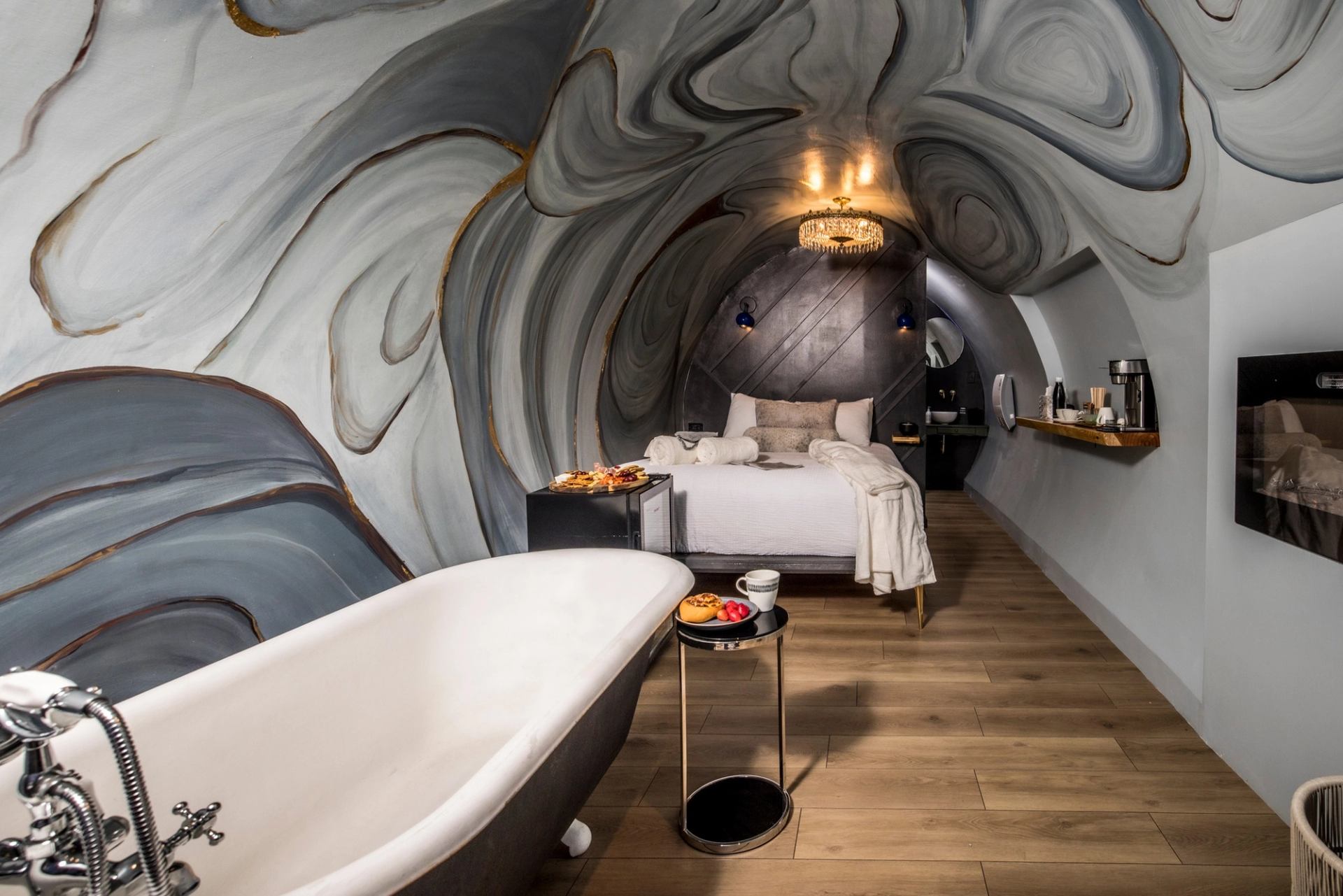 Indoor suite with sculpted wall mural, bed, chandelier, and kitchen counter at Obsidian Ridge.