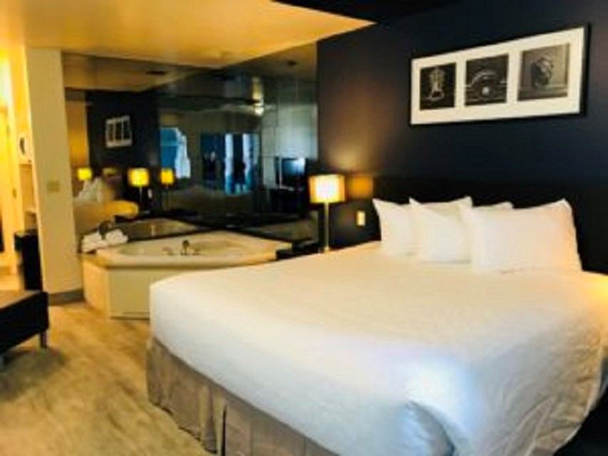 Modern hotel room with bed, jacuzzi tub, and warm lighting at Empire Inn & Suites.