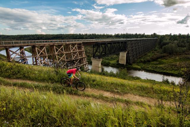 Cyclist with the Beaver River Trestle bridge in the background.