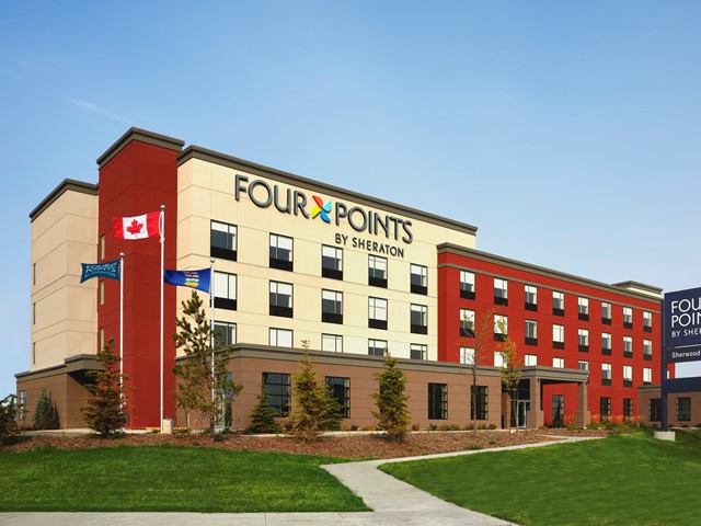 Exterior of Four Points by Sheraton Sherwood Park with flags and landscaped entrance.
