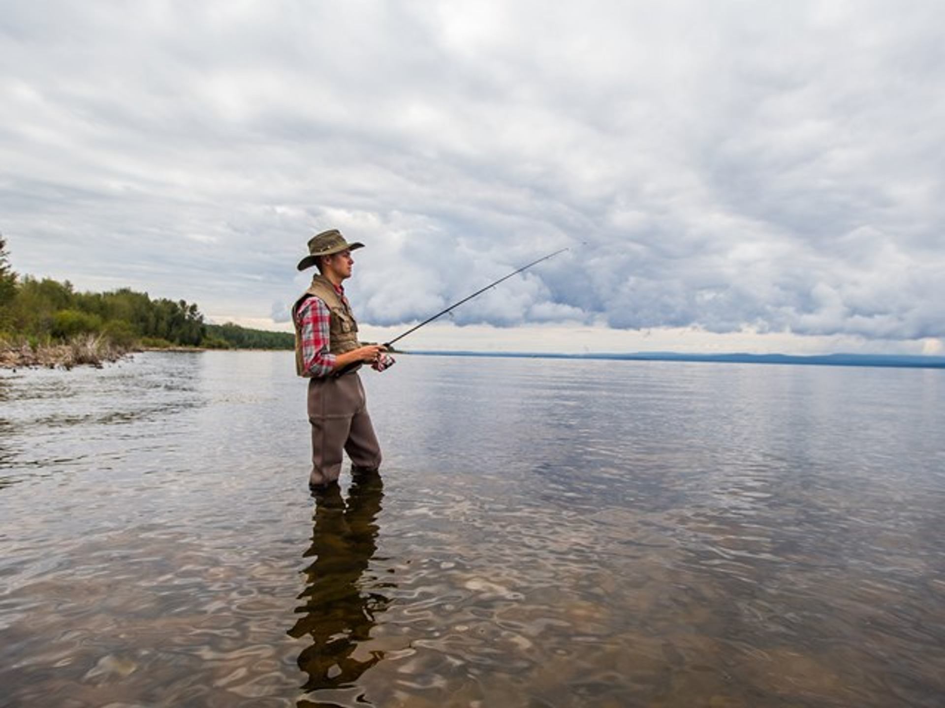 A young man fishes from the shore of Lesser Slave Lake.