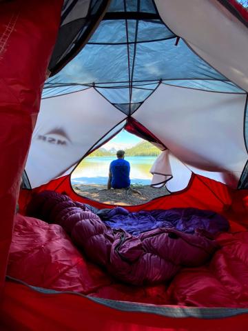 Person enjoying the view of the lake in front of their tent.