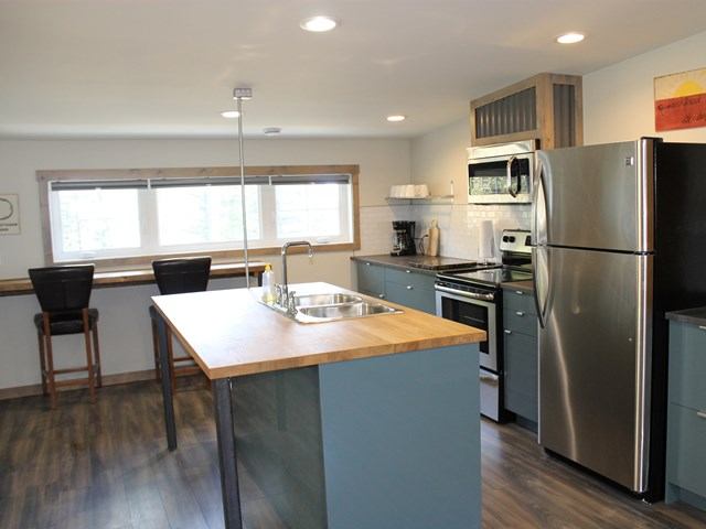 Modern kitchen with blue cabinets, wood countertops, stainless appliances, and large island sink.