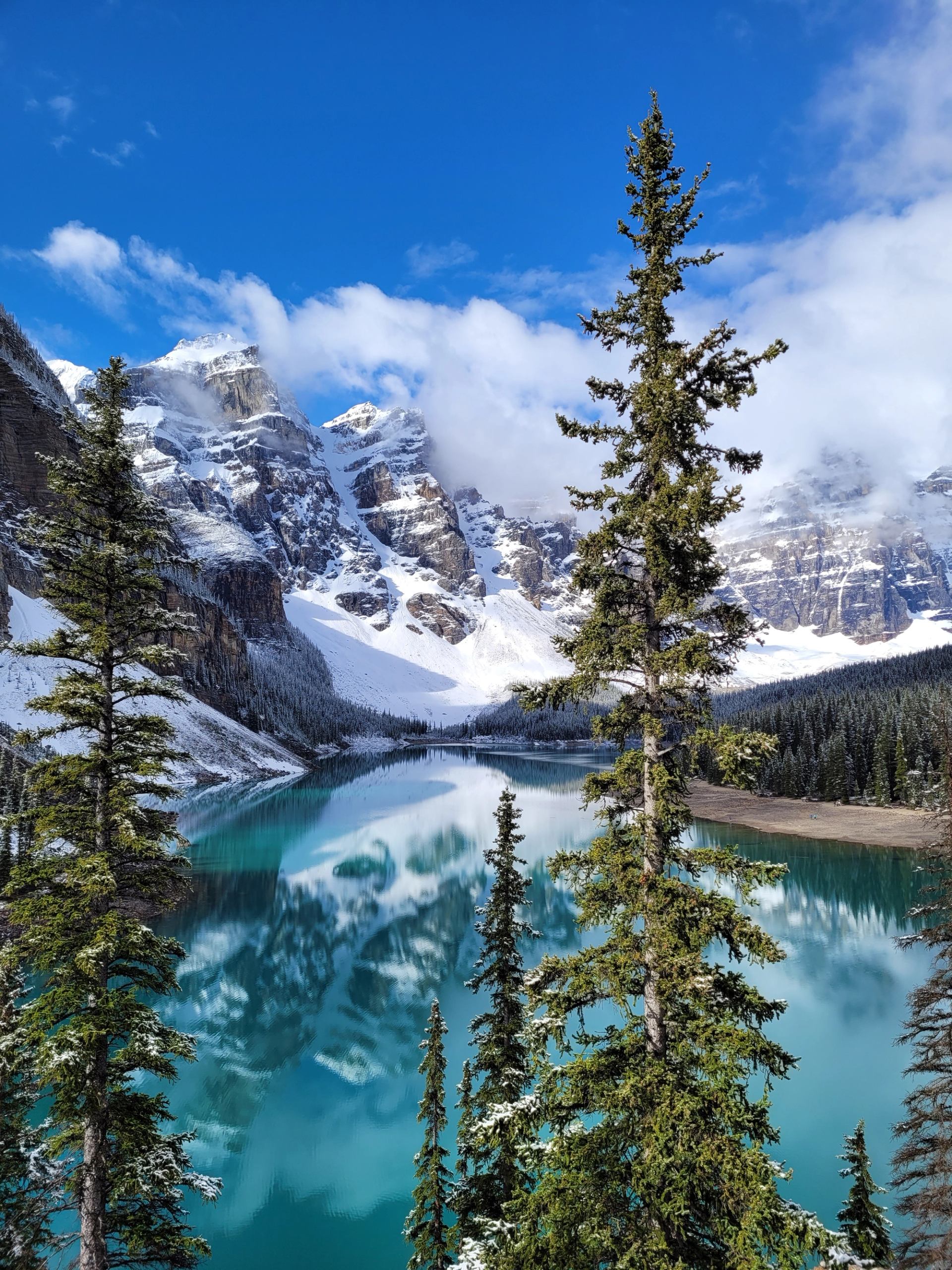 Snowy mountains reflecting in the turquoise water of Moraine Lake.