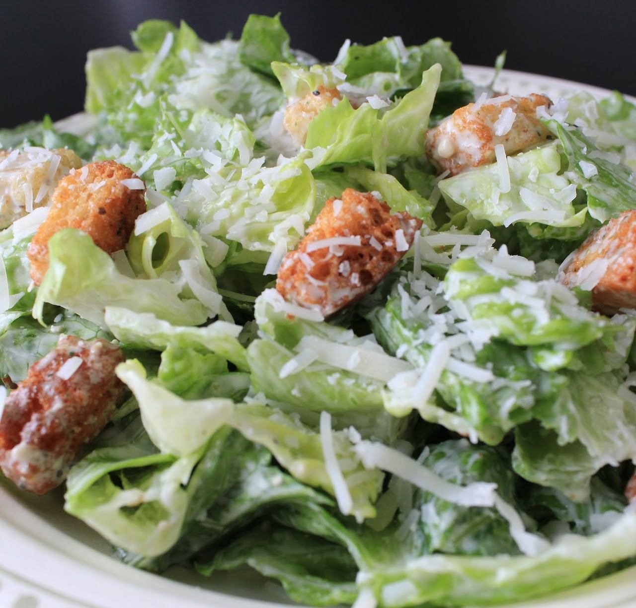 Close-up of Caesar salad with romaine lettuce, croutons, and shredded cheese.