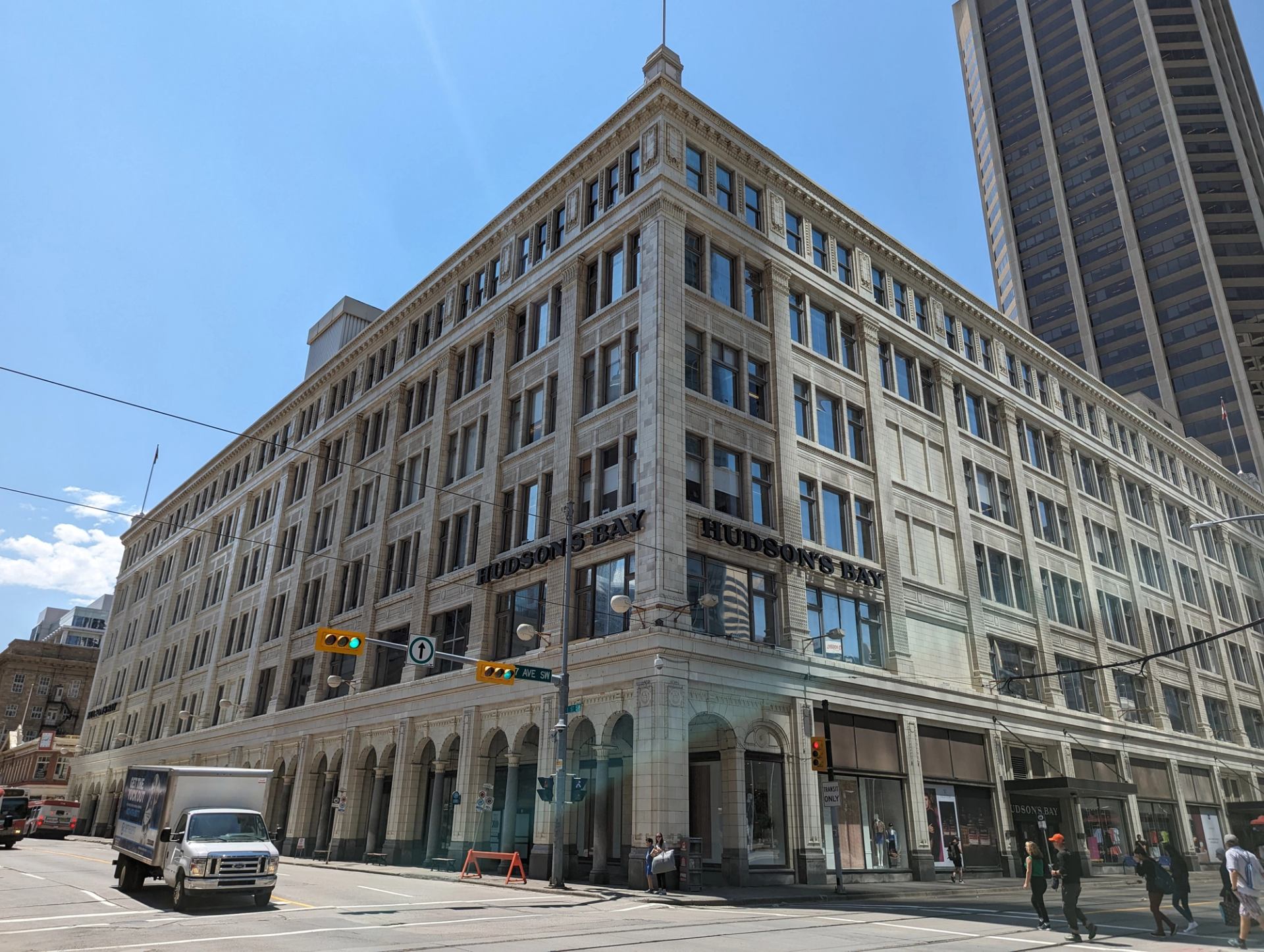 Hudson’s Bay department store on busy downtown street with pedestrians and vehicles.