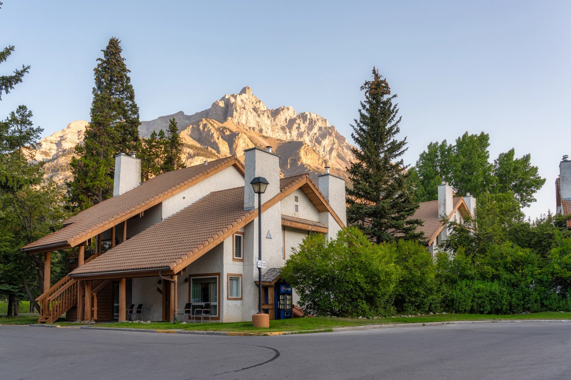 Condos with lots of greenery and a mountain in the background with the reflection of the sun.