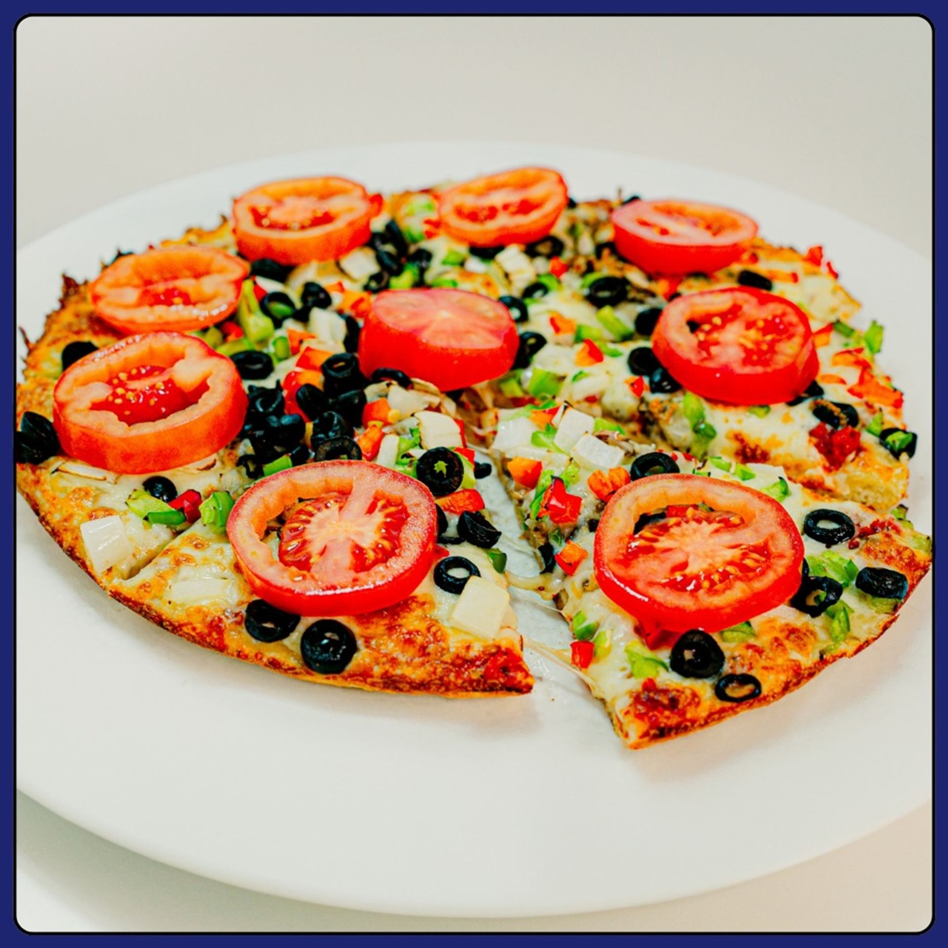 Pan pizza with mushrooms, onions, black olives, red and green peppers, and fresh tomatoes.