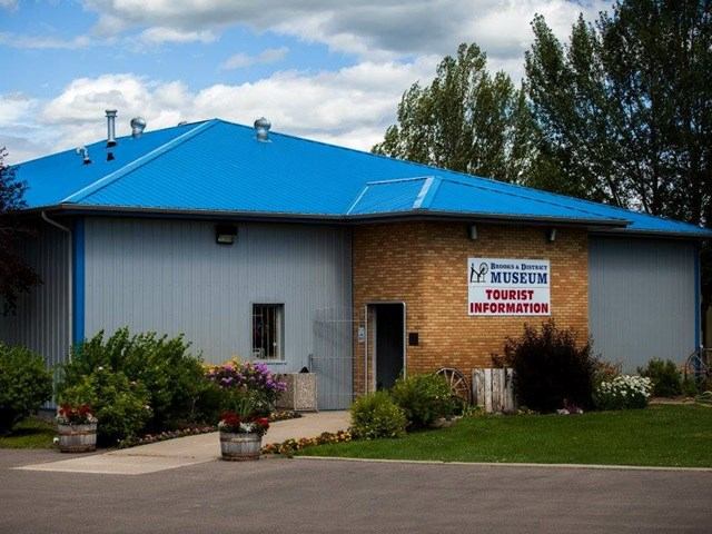Blue-roofed building labeled "Museum Tourist Information" with greenery around it.