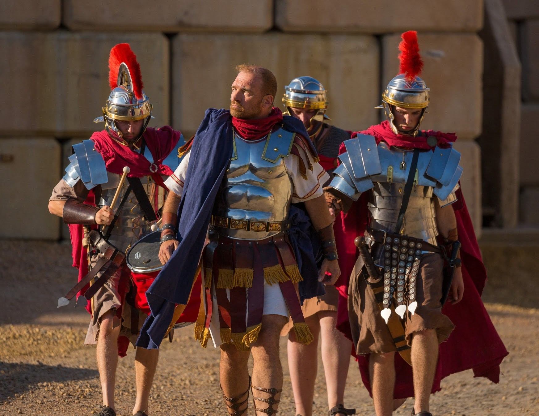 Actors in Roman soldier armour and red capes enter the stage area of the Badlands Passion Play