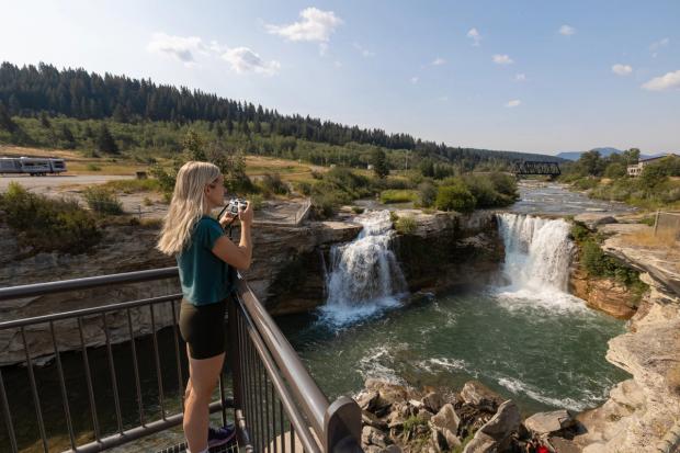 A woman takes a photo at Lundbreck Falls Campground.