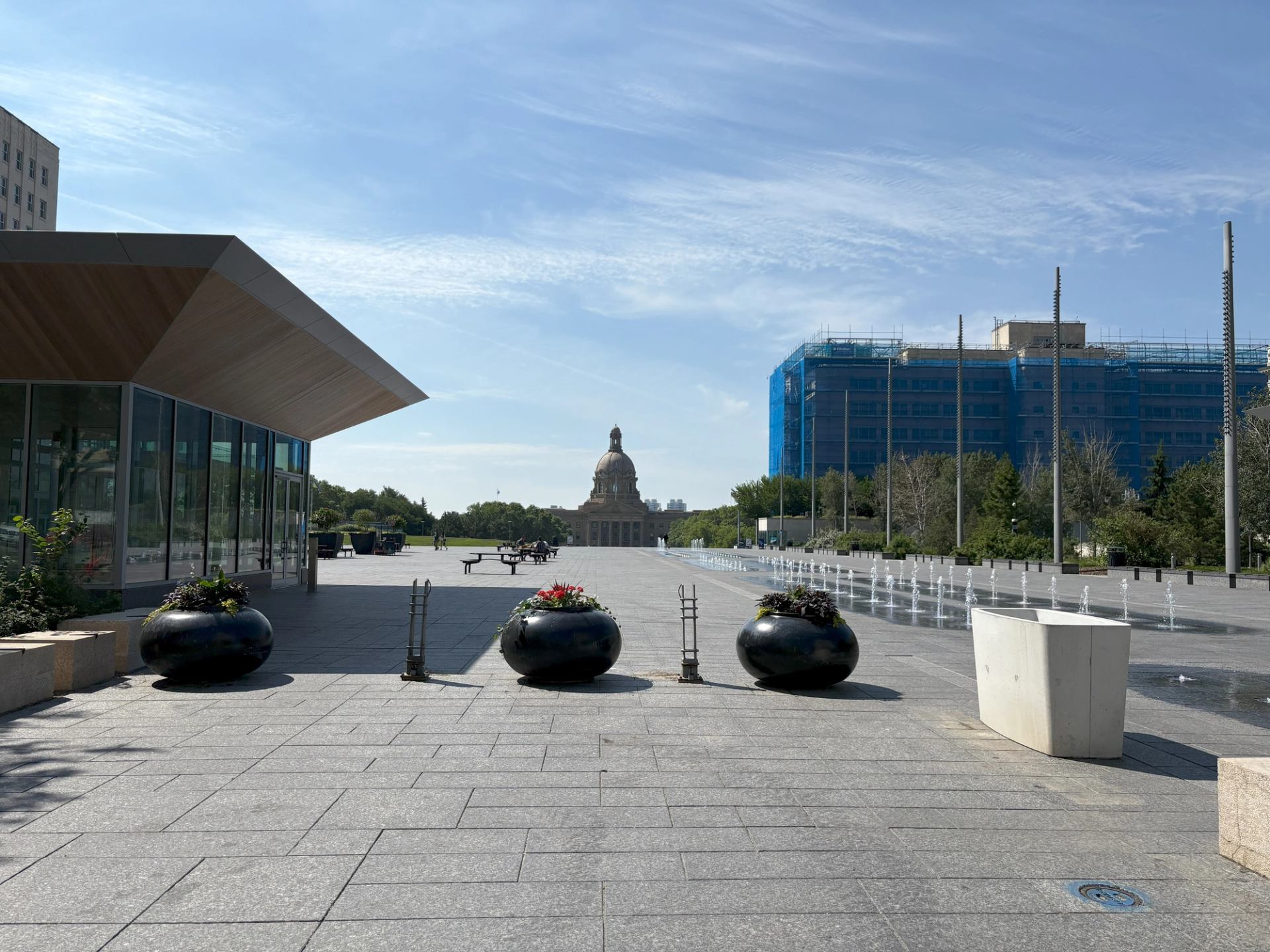 Urban path leading to domed building, flanked by modern architecture and planters.