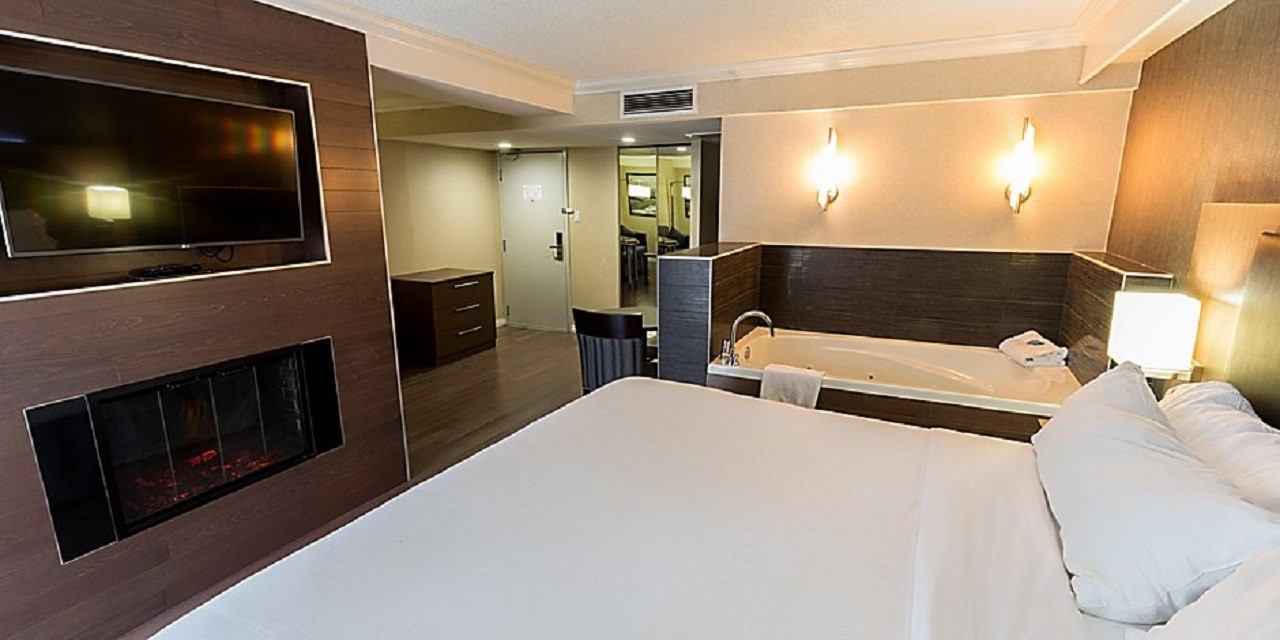 Cozy hotel room with a king bed, TV, and in-room whirlpool tub.