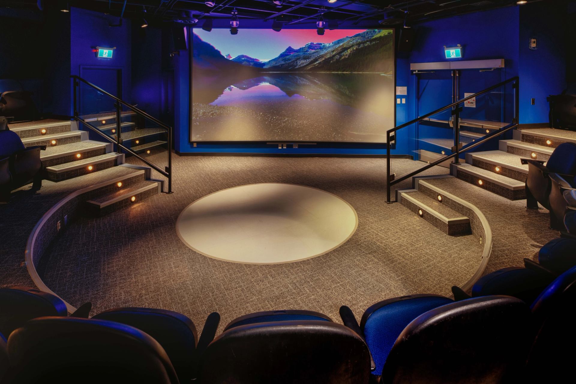 Small theater with tiered seating and a large screen showing a scenic mountain view.