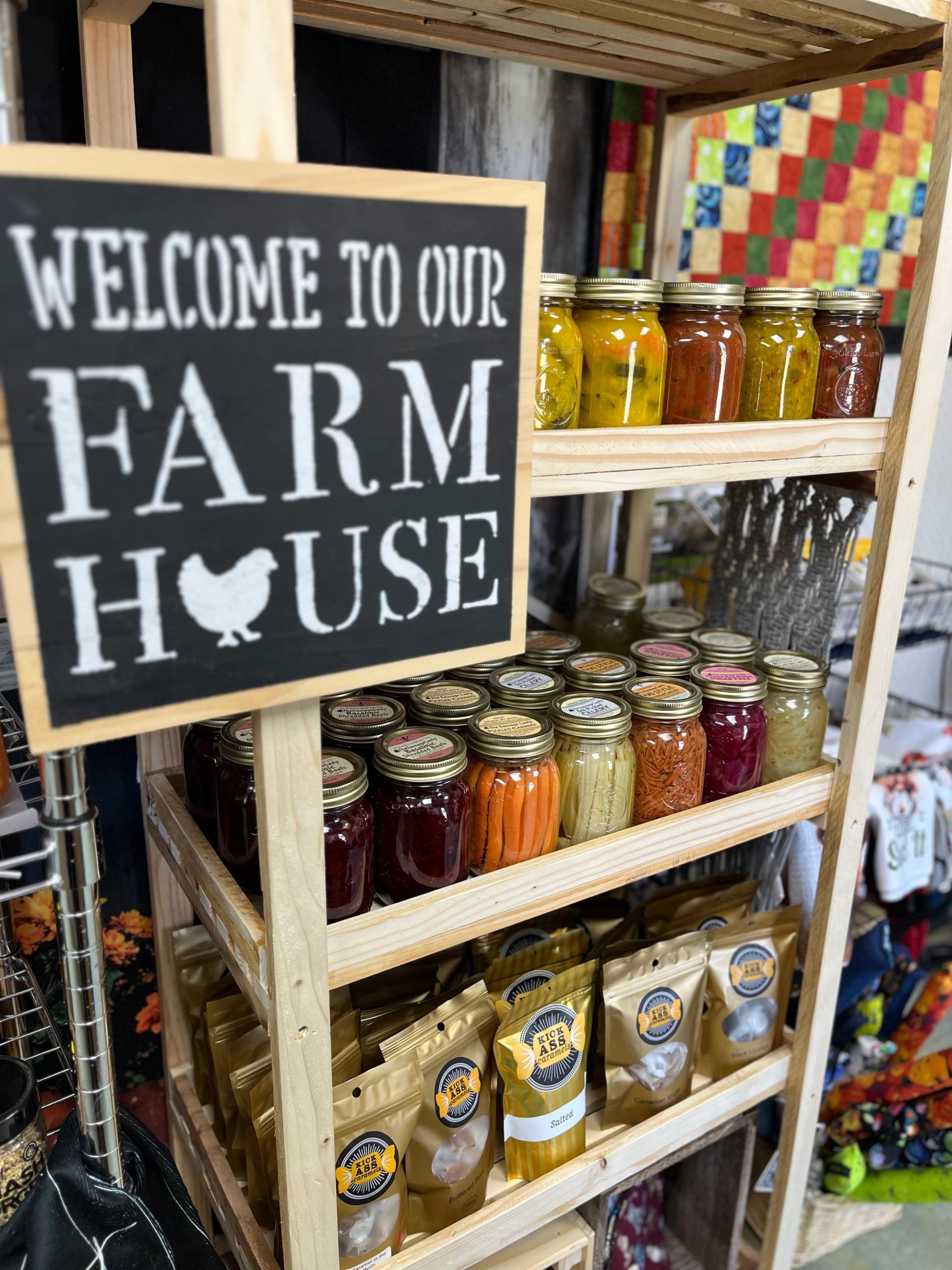 Wooden shelf with jars of preserves and a sign reading “Welcome to Our Farm House.”