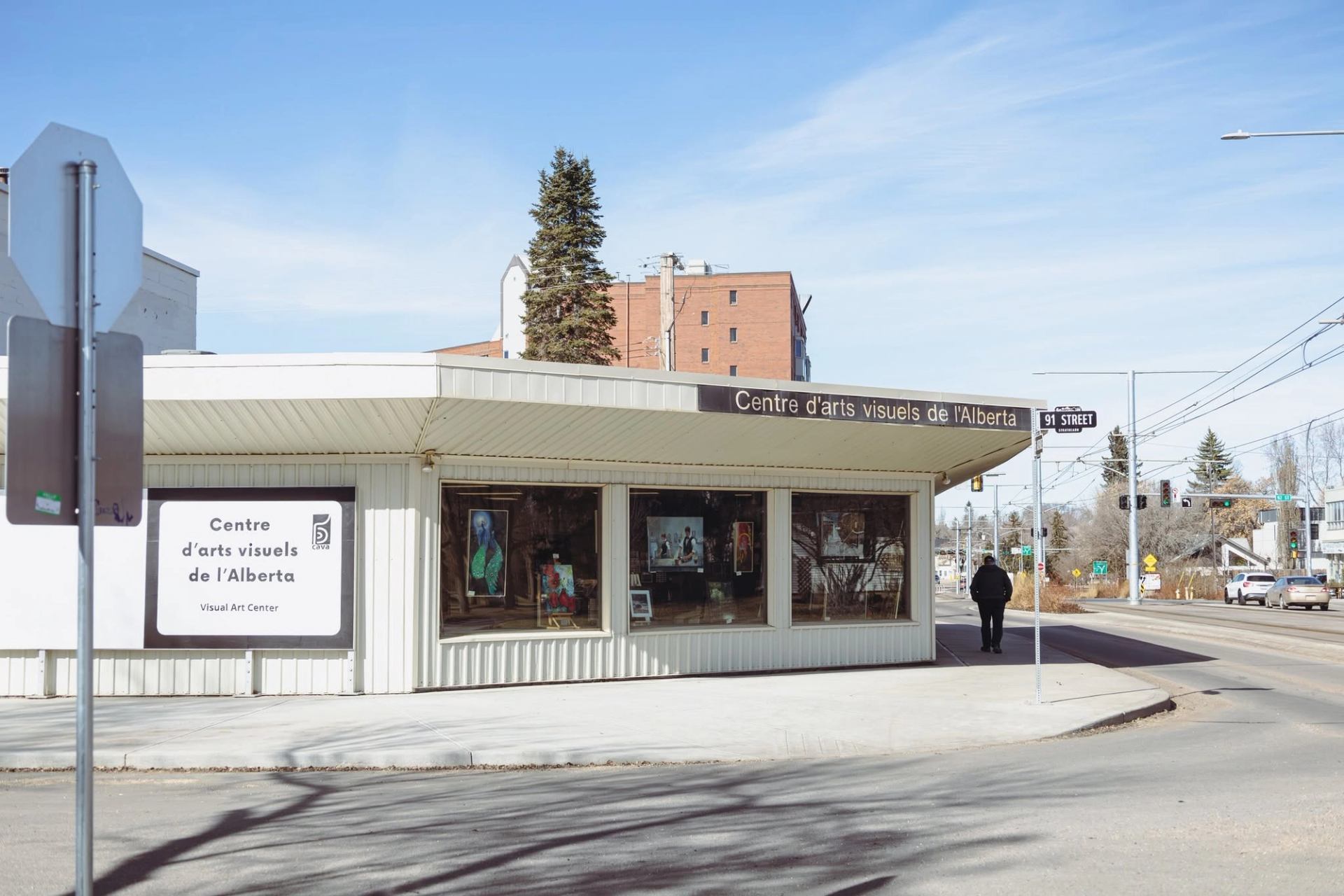 A visitor walks past Centre d'arts visuels de l'Alberta with artwork visible through windows.