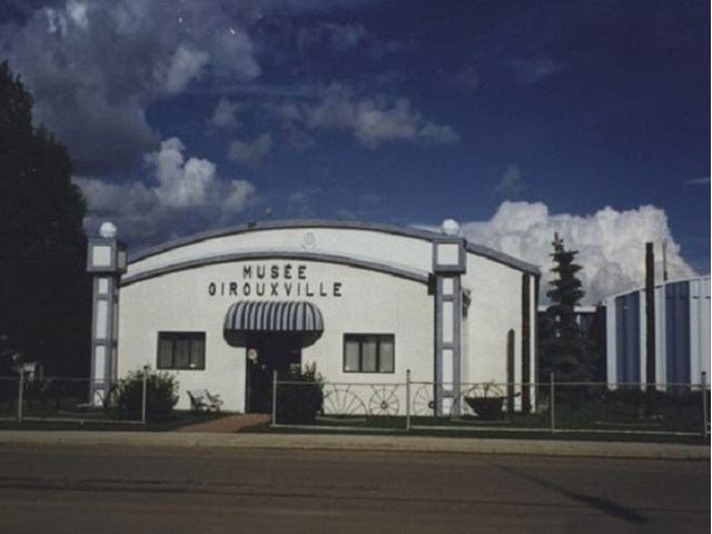 White museum building with striped awning and curved roof.