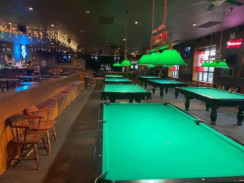 Interior of Better Than Fred’s with green-lit pool tables and a long bar.